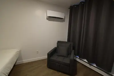 a room with a chair and a air conditioner at Motel ANF in Drummondville