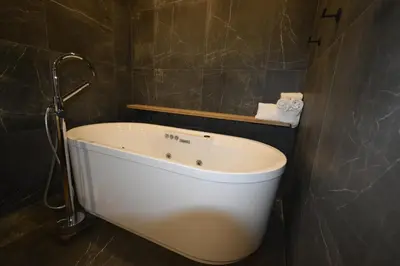 a bath tub in a bathroom with brown tiles at Motel ANF in Drummondville