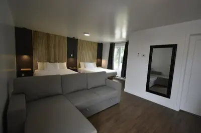a living room with a couch and a bed and a mirror at Motel ANF in Drummondville