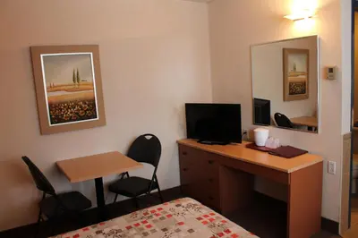 a bedroom with a desk and a bed and a desk and a computer at Motel Capri & Suites in Repentigny