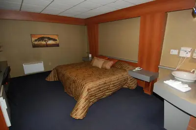 a hotel room with a bed and a sink at Motel Capri & Suites in Repentigny