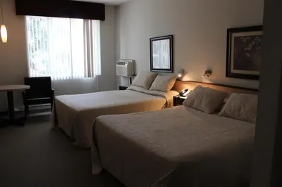 a hotel room with two beds and a table at Motel Capri & Suites in Repentigny