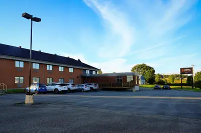 a building with cars parked in a parking lot at Hôtel Val-des-Sources in Asbestos