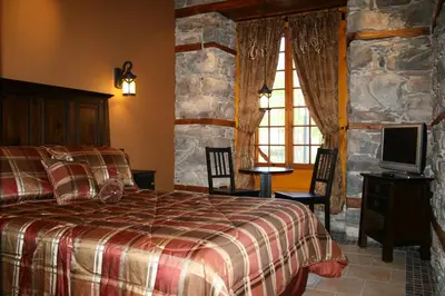 a bedroom with a bed and a tv and a stone wall at Manoir Ramezay in Marieville