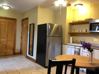 a kitchen with a stainless steel refrigerator and a table at Manoir Ramezay in Marieville