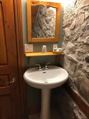 a bathroom with a sink and a stone wall at Manoir Ramezay in Marieville