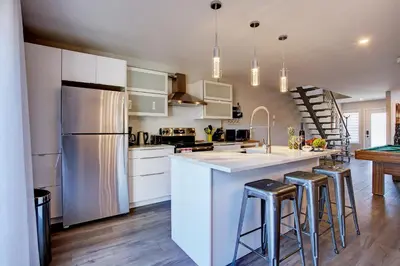 a kitchen with white cabinets and a kitchen island with bar stools at Modern Townhouse with Rooftop Deck in Montréal