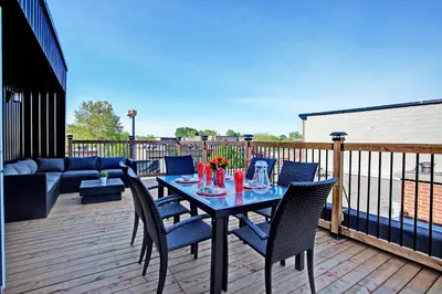 a wooden deck with a table and chairs on it at Modern Townhouse with Rooftop Deck in Montréal