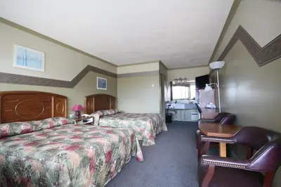 a hotel room with two beds and a desk at Motel Marie-Dan in Sainte-Eulalie
