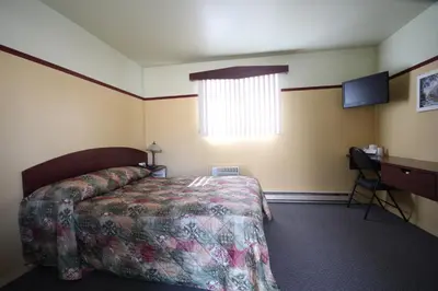 a bedroom with a bed and a desk and a window at Motel Marie-Dan in Sainte-Eulalie