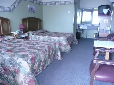 a hotel room with two beds and a television at Motel Marie-Dan in Sainte-Eulalie
