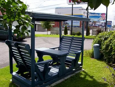 a blue bench with a picnic table in the grass at Motel Montgolfière JP in Saint-Jean-sur-Richelieu