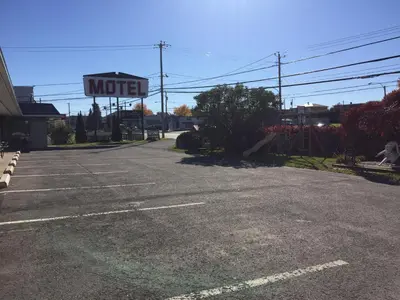 an empty parking lot with a motel sign in the background at Motel Montgolfière JP in Saint-Jean-sur-Richelieu