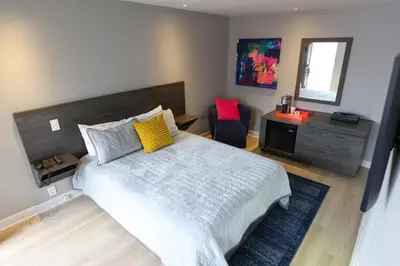 a bedroom with a large bed and a chair at Le Fabreville Motel & Suites in Laval