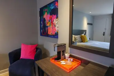 a room with a mirror and a chair and a bed at Le Fabreville Motel & Suites in Laval