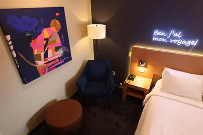 a hotel room with a bed and a blue chair at Le Fabreville Motel & Suites in Laval