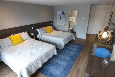 a bedroom with two beds and a blue rug at Le Fabreville Motel & Suites in Laval