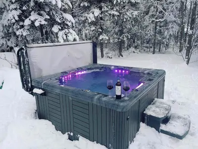 a hot tub with two glasses of wine in the snow at Chalets du Domaine - RUSTIQUE in Notre-Dame-Des-Bois