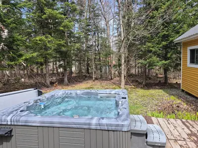 a hot tub sitting on a deck in a yard at Chalets du Domaine - RUSTIQUE in Notre-Dame-Des-Bois