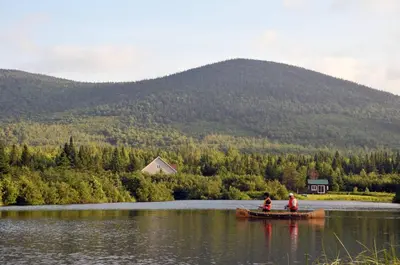 two people in a boat on a lake with a mountain at Chalets du Domaine - RUSTIQUE in Notre-Dame-Des-Bois