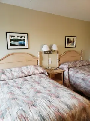 a hotel room with two beds and a table at Hotel Transit in Mont-Saint-Hilaire