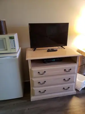 a television on top of a dresser with a microwave at Hotel Transit in Mont-Saint-Hilaire