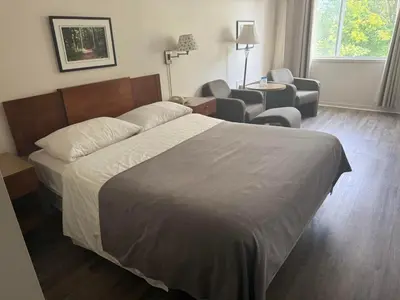 a hotel room with a bed and a chair at Hotel Transit in Mont-Saint-Hilaire
