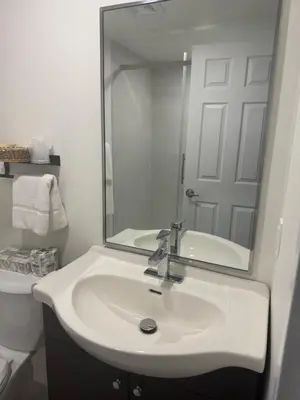 a white bathroom with a sink and a mirror at Hotel Transit in Mont-Saint-Hilaire
