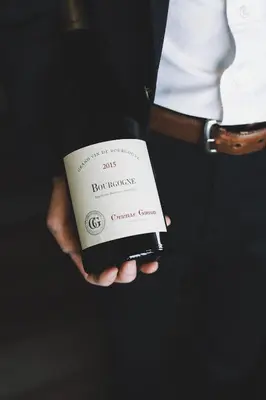 a man is holding a bottle of wine at Hôtel Rive Gauche in Beloeil Village