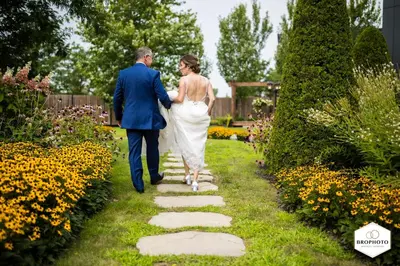a bride and groom walking through a garden at Hôtel Rive Gauche in Beloeil Village