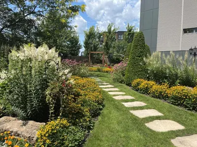 a garden with colorful flowers and a walkway at Hôtel Rive Gauche in Beloeil Village
