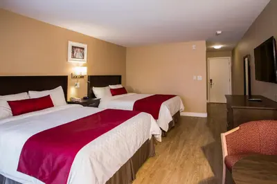 a hotel room with two beds and a chair at Hotel Bromont in Bromont