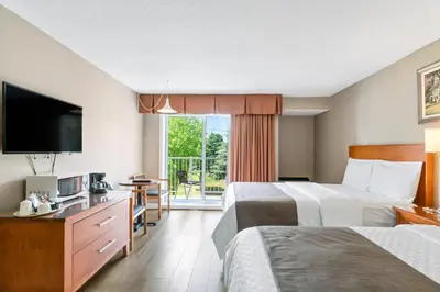 a hotel room with two beds and a flat screen tv at Hotel Bromont in Bromont