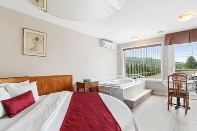 a bedroom with a bed and a tub and a sink at Hotel Bromont in Bromont