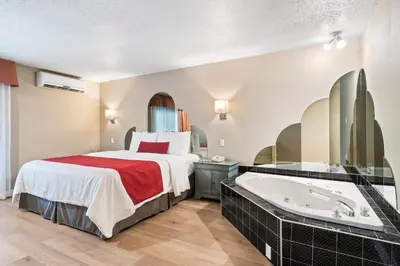 a hotel room with a bed and a bathtub at Hotel Bromont in Bromont