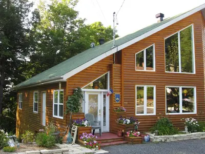 a small wooden house with a porch and a door at Le Gite A Margot in Bromont