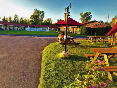a group of picnic tables and umbrellas in a park at Hotel Motel Bonsoir in Granby