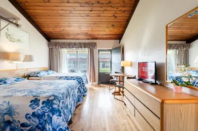 a hotel room with two beds and a mirror at Hotel Motel Bonsoir in Granby