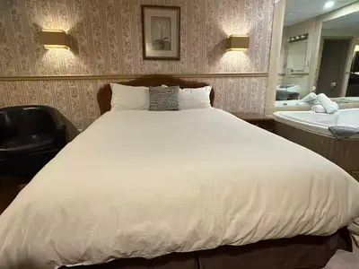 a bedroom with a large white bed and a sink at Hotel Motel La Marquise in Sherbrooke