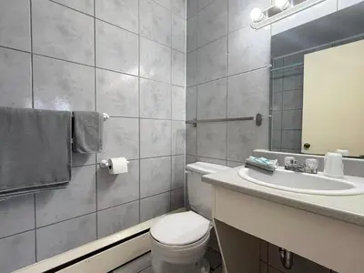 a bathroom with a toilet and a sink and a mirror at Hotel Motel La Marquise in Sherbrooke