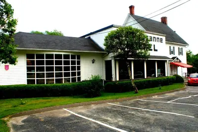 a white house with a parking lot in front of it at Motel & Hotel La Paysanne in Sherbrooke