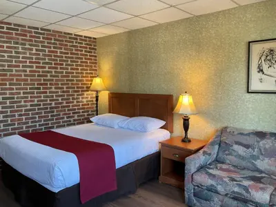 a hotel room with a bed and a chair at Motel & Hotel La Paysanne in Sherbrooke