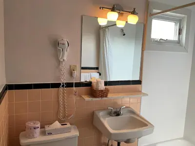 a bathroom with a sink and a phone on the wall at Motel & Hotel La Paysanne in Sherbrooke