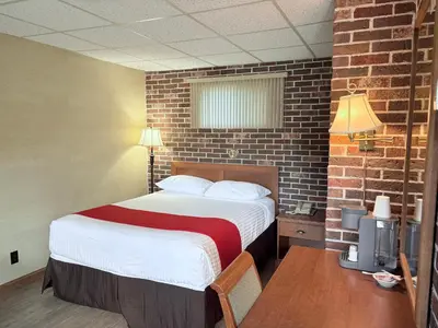 a bedroom with a bed and a brick wall at Motel & Hotel La Paysanne in Sherbrooke