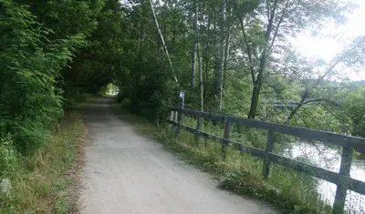 a dirt road next to a fence next to a river at Motel & Hotel La Paysanne in Sherbrooke