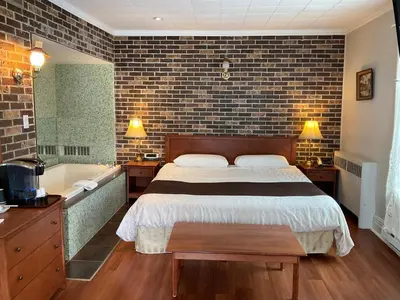 a bedroom with a bed and a bathtub and a bed and a television at Motel & Hotel La Paysanne in Sherbrooke