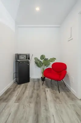 a red chair in a room with a kitchen at Motel Champlain in Brossard