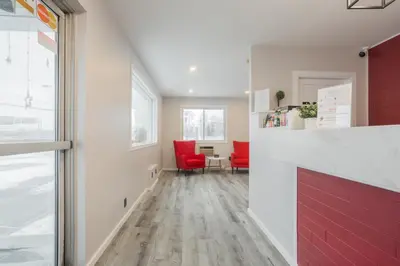 a hallway with red chairs and a table in a room at Motel Champlain in Brossard