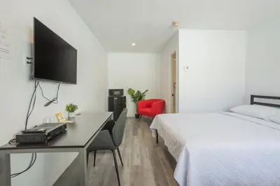 a hotel room with a bed and a desk with a tv at Motel Champlain in Brossard