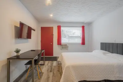 a bedroom with a bed and a desk and a window at Motel Champlain in Brossard